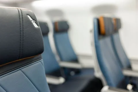 Close-up of the stitched dark headrest and blue upholstery, with other seats in soft focus.