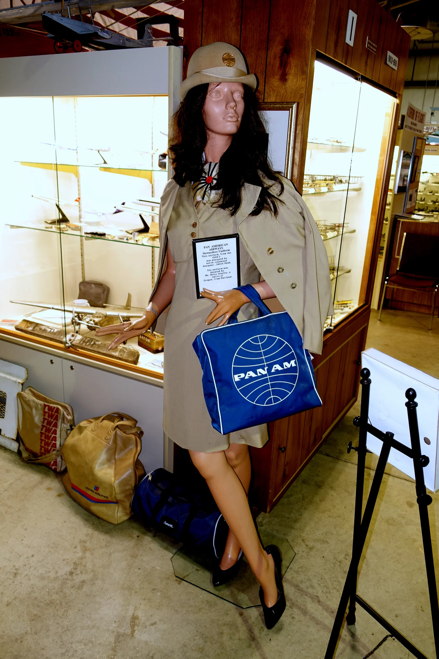 Museum mannequin in a beige Pan Am uniform and hat, carrying a blue Pan Am flight bag.
