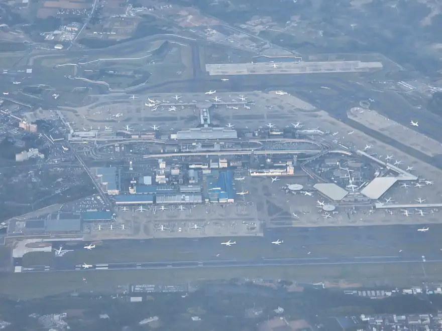 Narita Airport terminal buildings and apron surrounded by green countryside