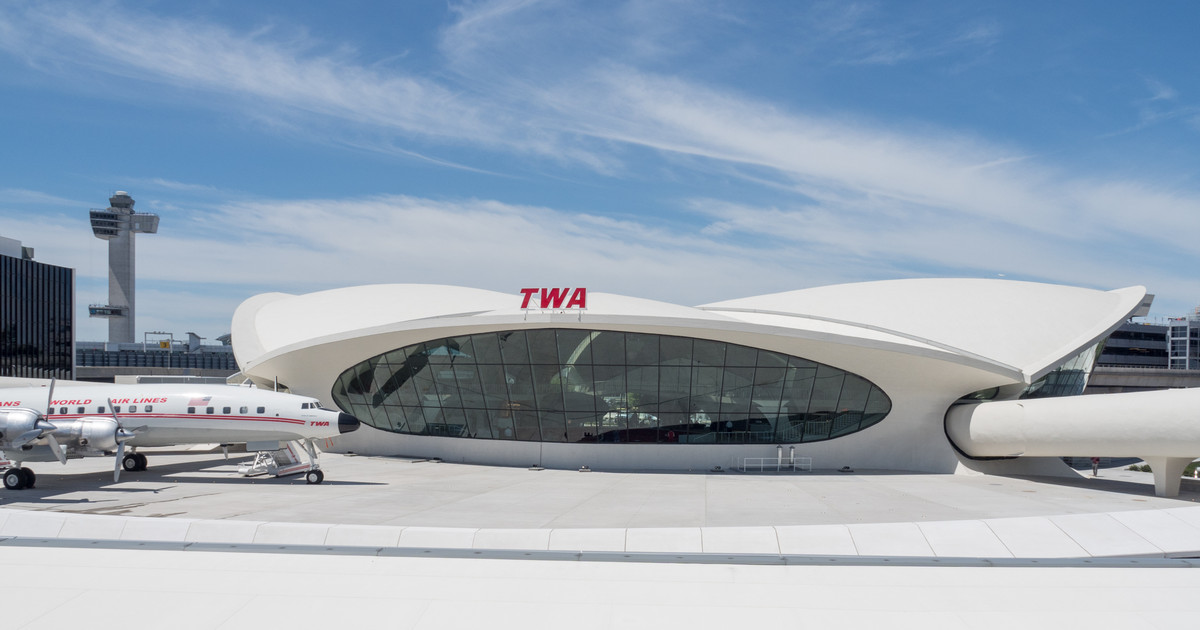 White sculptural TWA Flight Center at JFK, its red TWA lettering above the glass facade and Connie parked to one side.